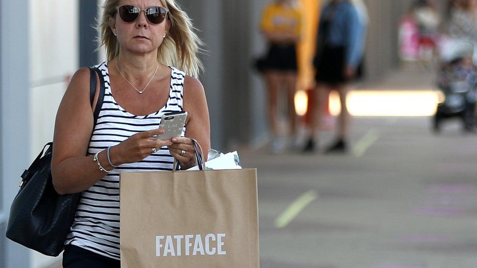 A shopper holds a Fat Face bag at Rushden Lakes outlet