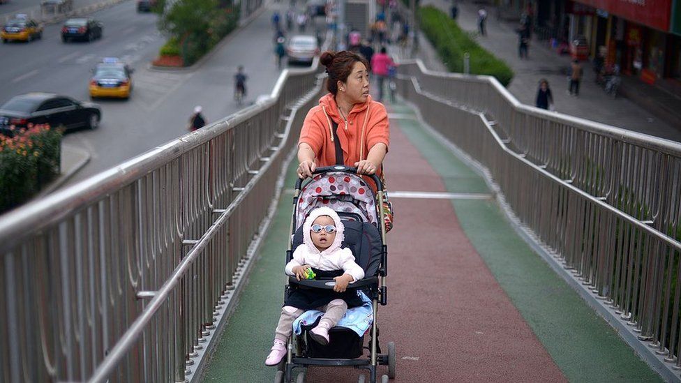 A woman pushes a baby carriage on an overpass in Beijing.