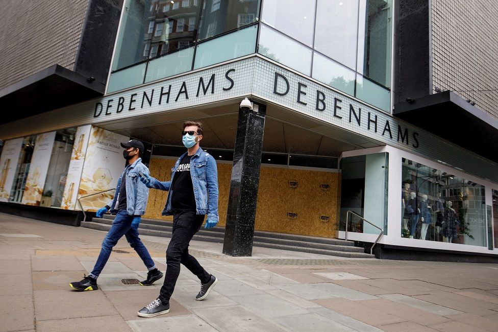 People walk past a boarded up Debenhams store