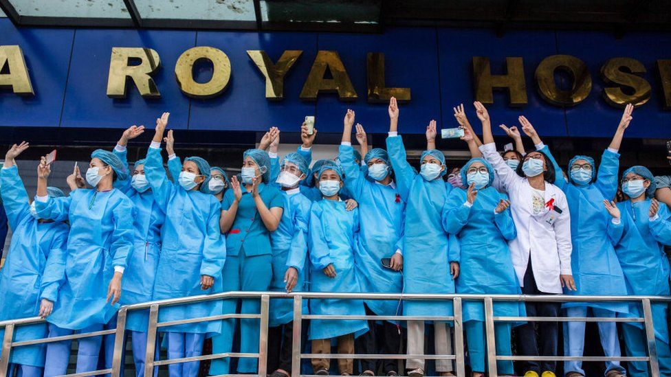 Медицинские работники больницы отдают честь тремя пальцами во время демонстрации против военного переворота. Огромная толпа вышла на улицы Янгона на второй день протеста против переворота и потребовала освобождения Аун Сан Су Чжи, поскольку правительство отключило интернет.