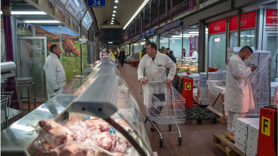 A worker chats with a trader as he pushes a trolley through Smithfield Market in February 2023