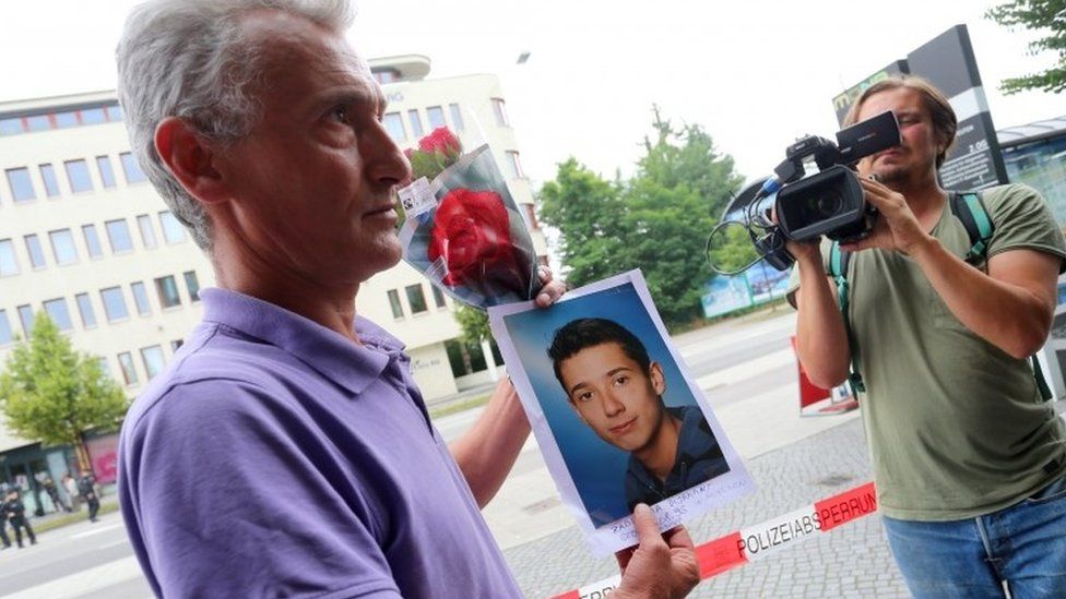 Naim Zabergja stands in front of the media holding a photo of his killed son Dijamant at the Olympia shopping centre where the shooting spree took place in Munich, Germany, 23 July 2016.