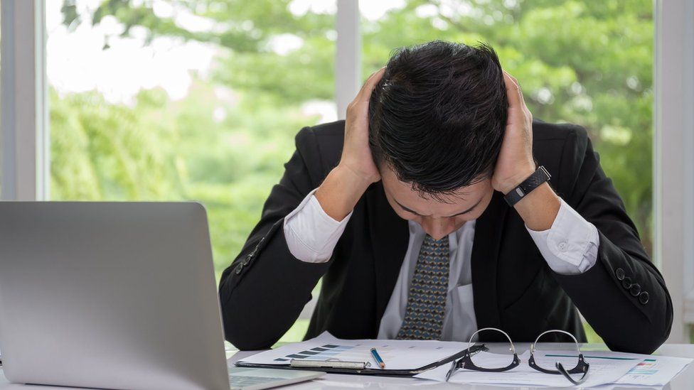 File photo: A stressed worker by his laptop