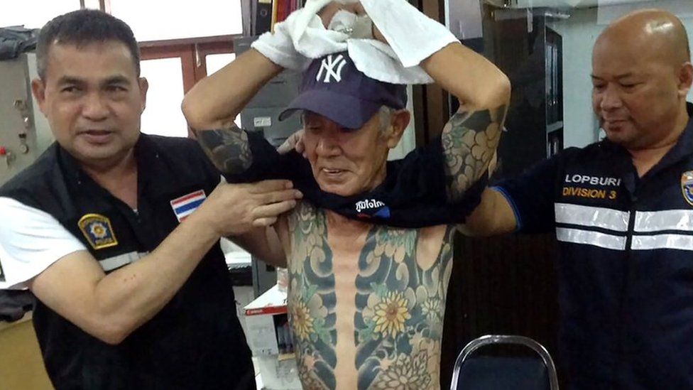 Thai policemen with Mr Shirai, displaying the tattoos on his body