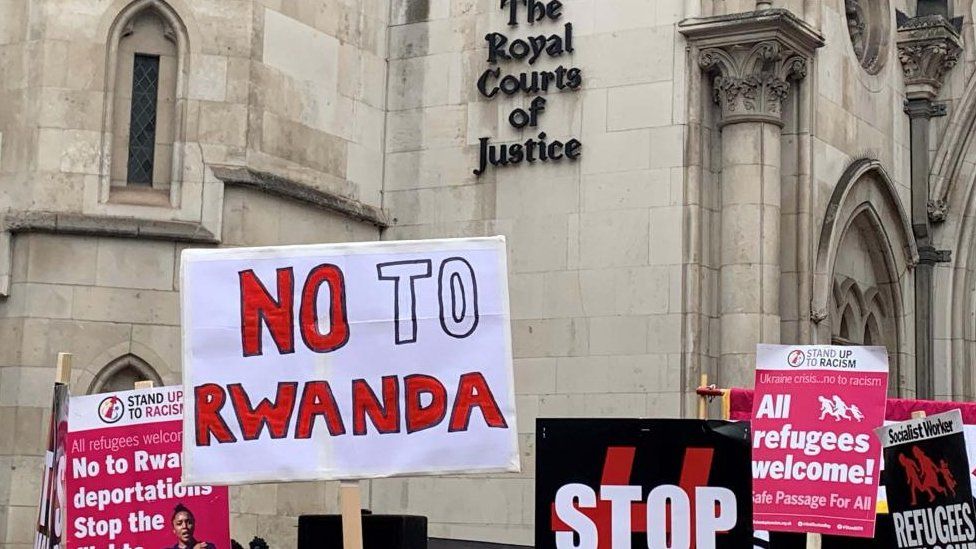 People seen holding placards to protest the Rwanda asylum policy outside the Royal Courts of Justice