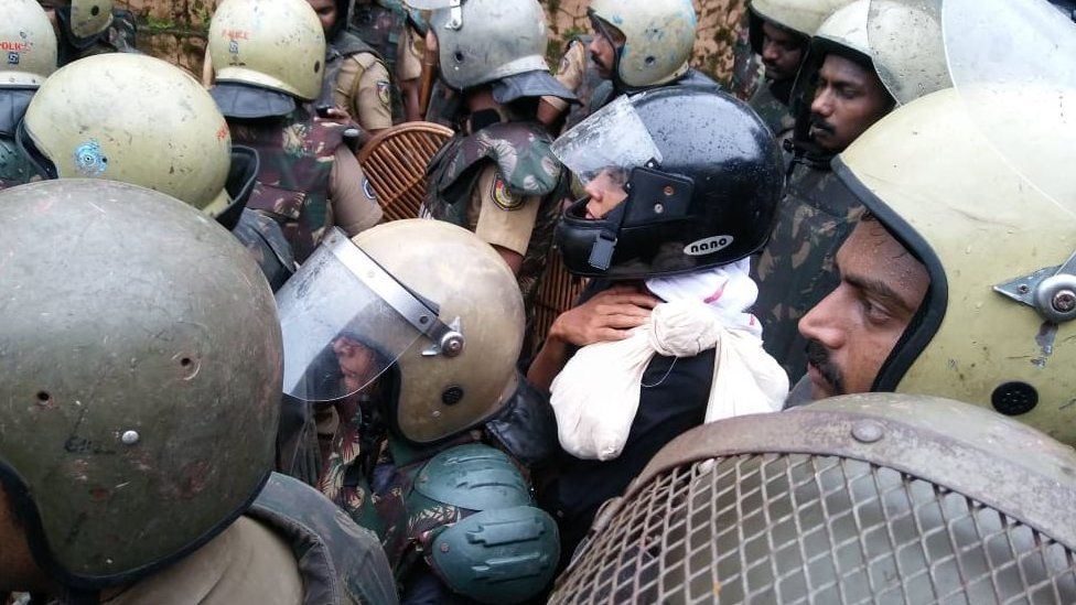 Two women trying to enter the temple in full riot gear