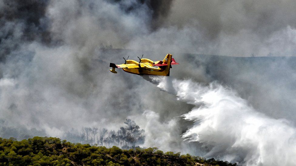 Amphibious aircraft designed for aerial firefighting drop water over wildfires in Greece