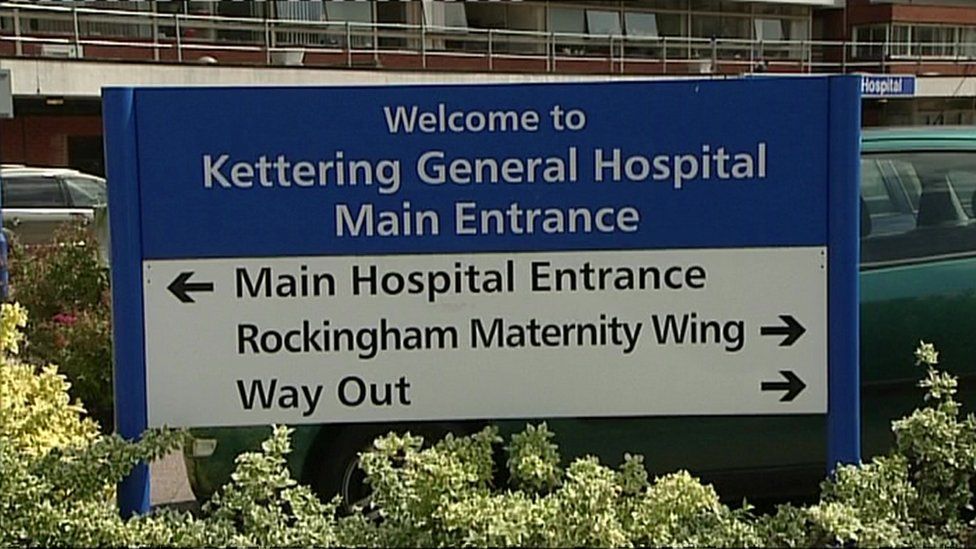 A sign at the entrance to Kettering General Hospital. It shows directions to the main entrance, the maternity wing and the exit