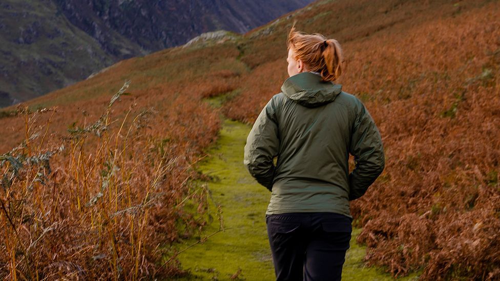 Red haired anonymous woman walks outside in rural UK setting