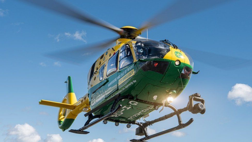 Yellow and green helicopter hovering with blue sky above