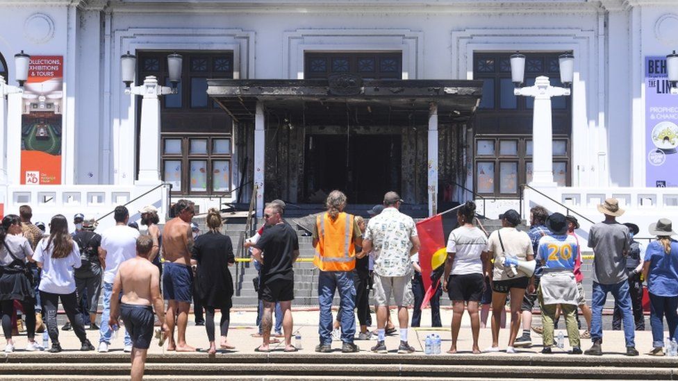 People stand in front of the burned out entrance doors to Old Parliament House in Canberra, Australia, 30 December 2021