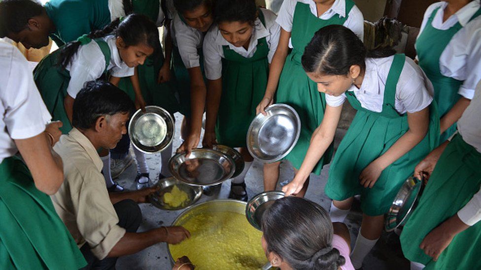 Школьницы получают бесплатную еду в середине дня в государственной школе в Нагаоне, штат Ассам