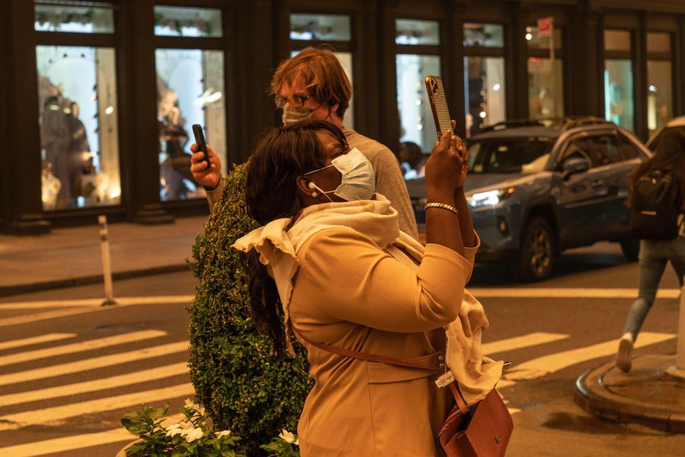 Menschen machen Fotos und tragen Gesichtsmasken am 7. Juni 2023 in New York, USA, wegen der schlechten Luftqualität, die durch den Rauch der kanadischen Waldbrände verursacht wird