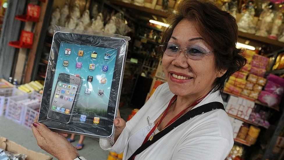 Shop owner Chow Kum Len shows off a paper replica iPad that is produced to be burnt as an offering to the dead during the Qing Ming festival in Kuala Lumpur on 6 April 2011