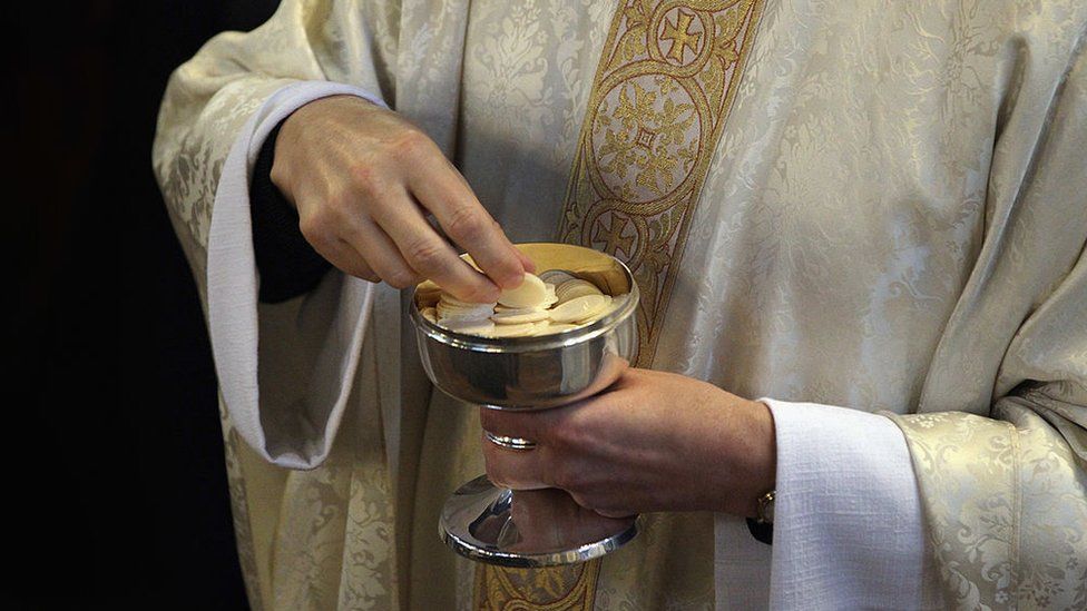 A priest holding communion wafers