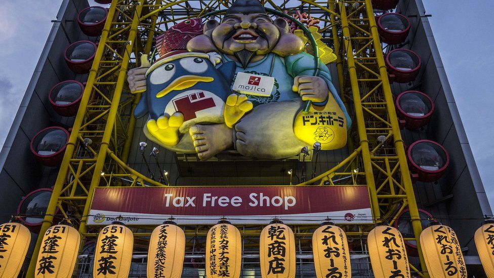 Facade outside a Donki store in Japan shows a figure holding the Donpen penguin mascot