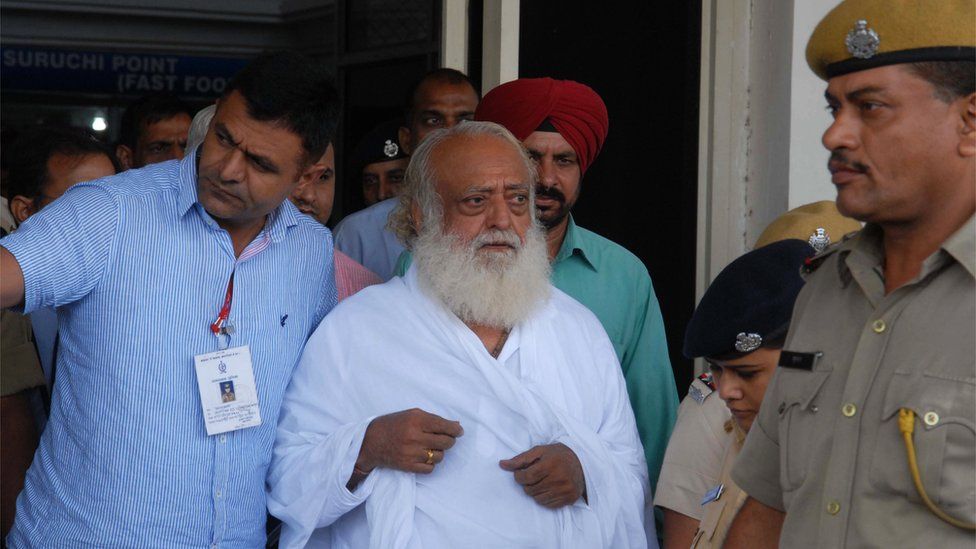 индийского духовного гуру Асарама Бапу (в центре) сопровождает полиция после того, как он был арестован в своем ашраме в Индоре, в аэропорту Джодхпура, 1 сентября 2013 г.