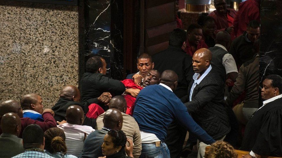 South African opposition party Economic Freedom Fighters MP Godrich Gardee (C, in red) is evicted with fellow EFF members during the South African president"s budget speech at the South African parliament in Cape Town on May 4, 2016.
