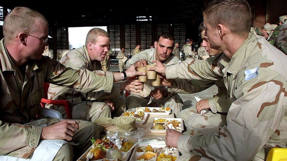 United States Army soldiers toast each other before eating Christmas dinner December 25, 2001 at Bagram Air Force Base