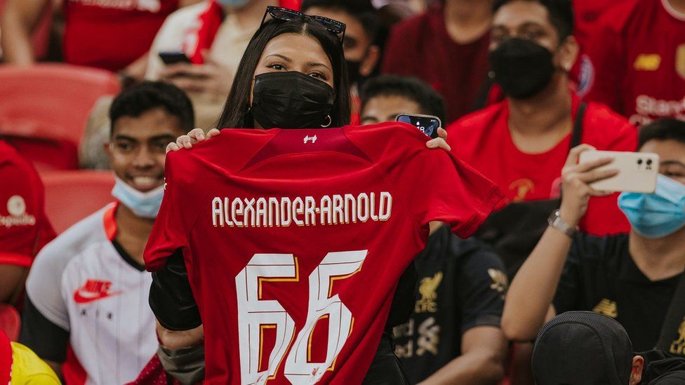 A Liverpool fan holds up a team shirt.