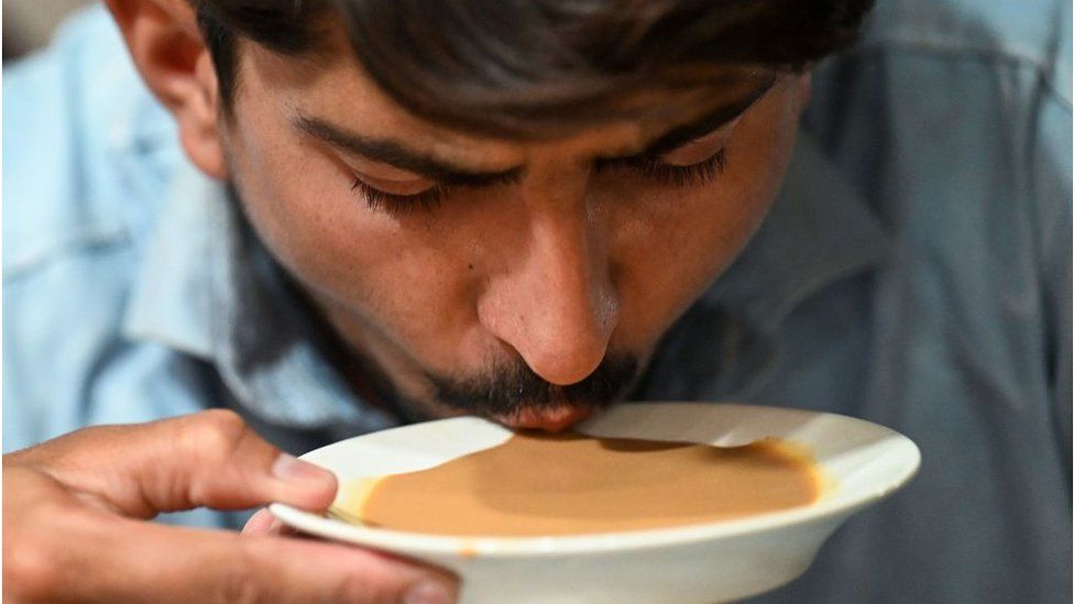 ชายคนหนึ่งดื่มชาจากจานรองที่ร้านอาหารในอิสลามาบัด