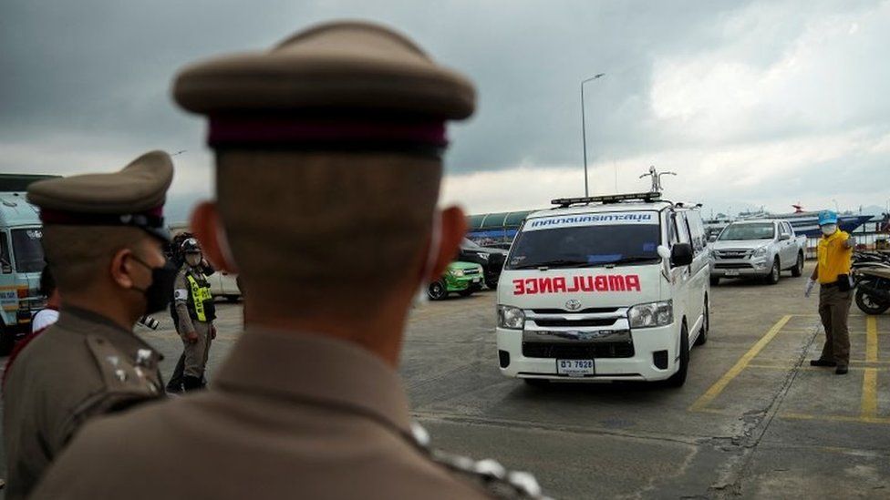 Thai police look on as an ambulance carrying the body of Australian cricket player Shane Warne leaves at a ferry port in Koh Samui, Thailand