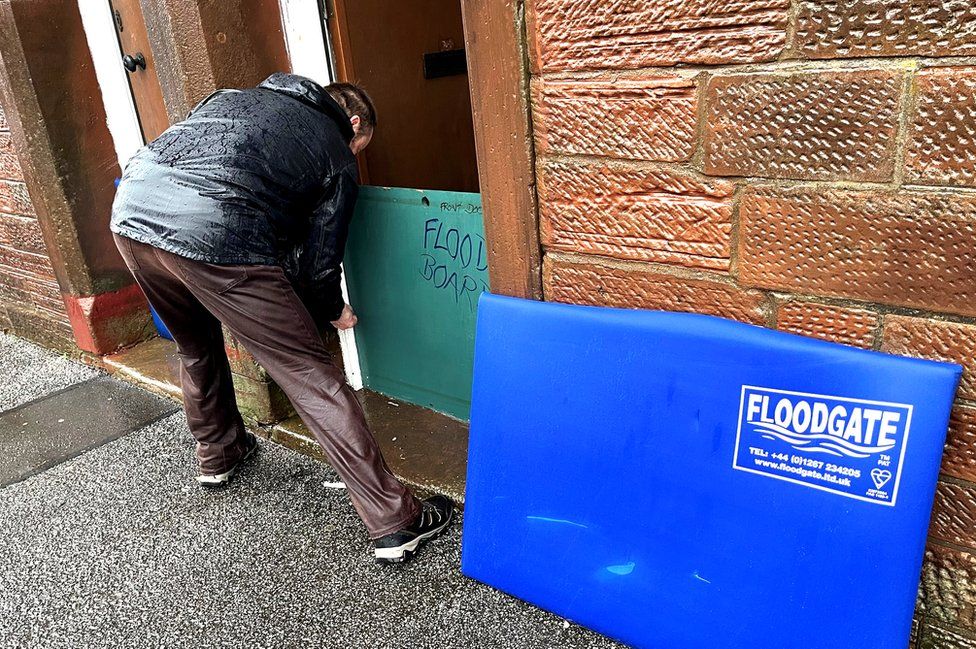 A man puts flood boards in place on his property at Whitesands, Dumfries