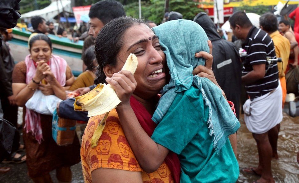 A woman cries as she holds her son after they were evacuated from a flooded area in Aluva, Kerala