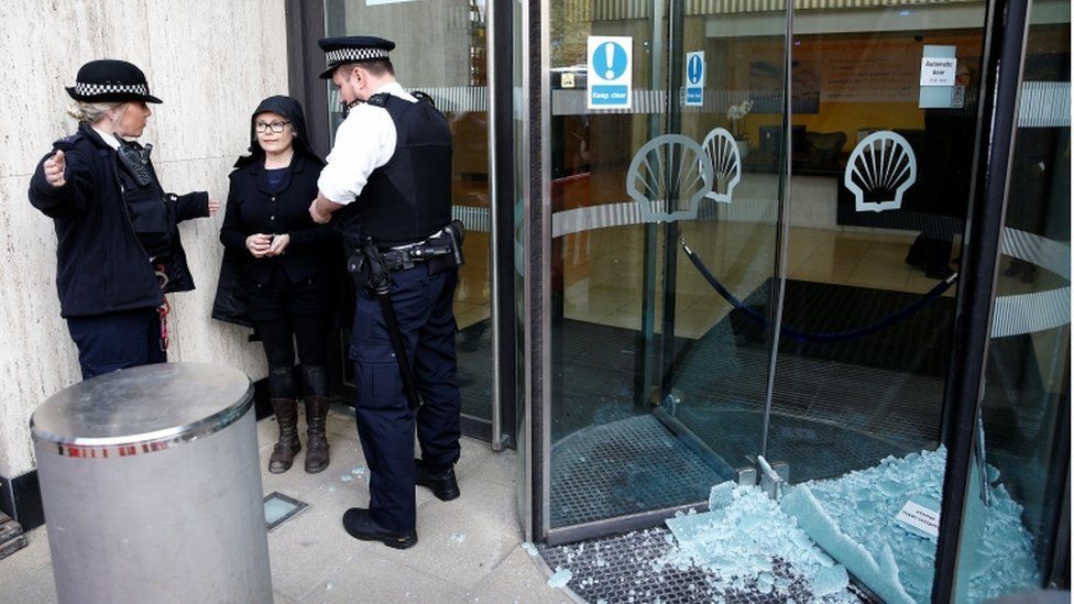 Police officers talk to a climate change activist outside Shell's London HQ