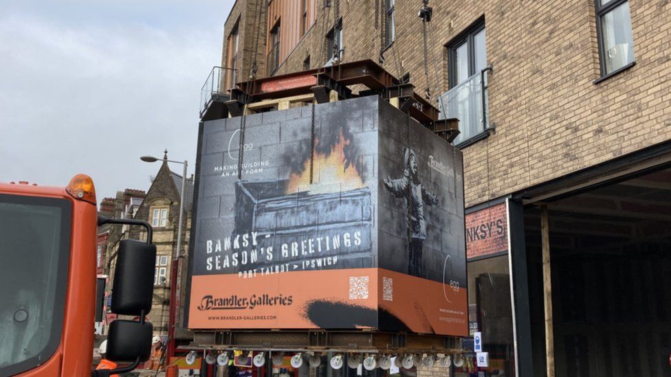 Season's Greetings by Banksy getting craned on to a lorry