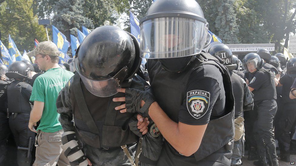 A police officer helps an injured colleague after protests in Kiev