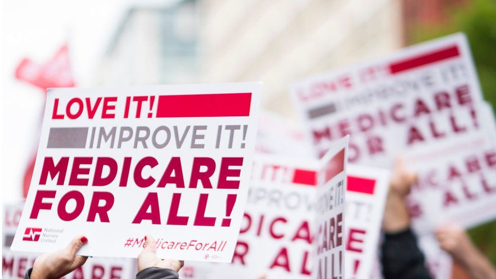 Members of National Nurses United union members wave "Medicare for All" signs during a rally in front of the Pharmaceutical Research and Manufacturers of America in Washington calling for "Medicare for All" in April 2019