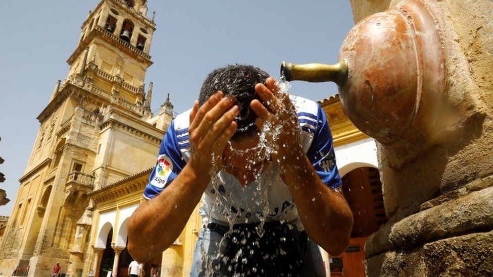 A man cools off in a fountain on a hot day in Cordoba, southern Spain, on 13 August 2021