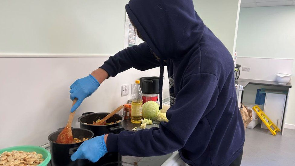 Two Saints kitchen visitor cooks food