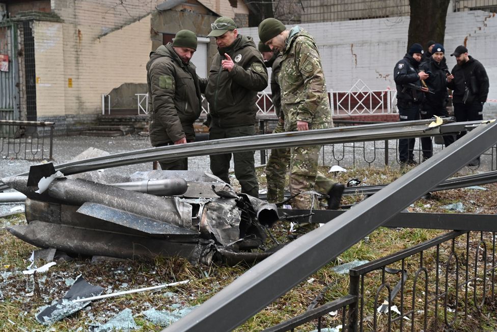 Police and security personnel inspect the remains of a shell in a street in Kyiv on 24 February 2022