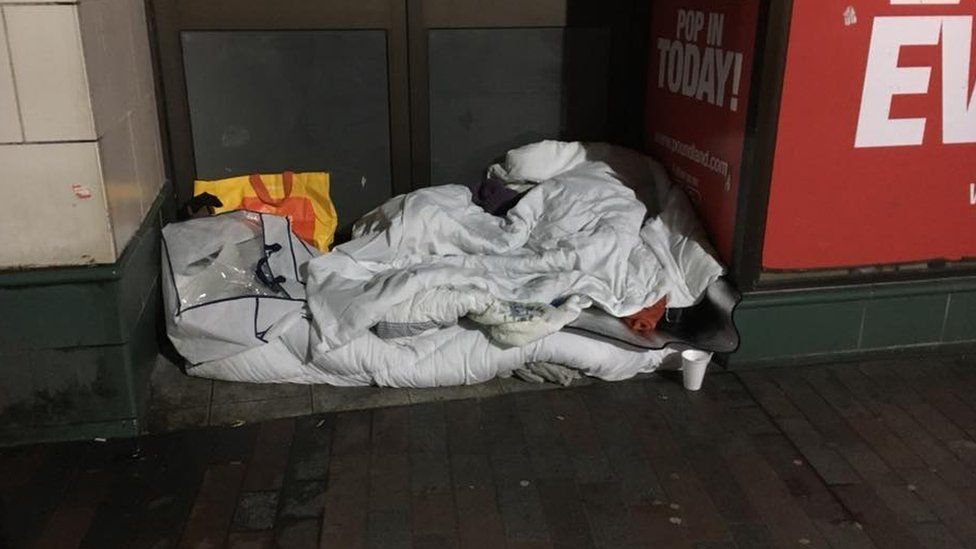 Picture of homeless woman in Northampton under wet bedding.