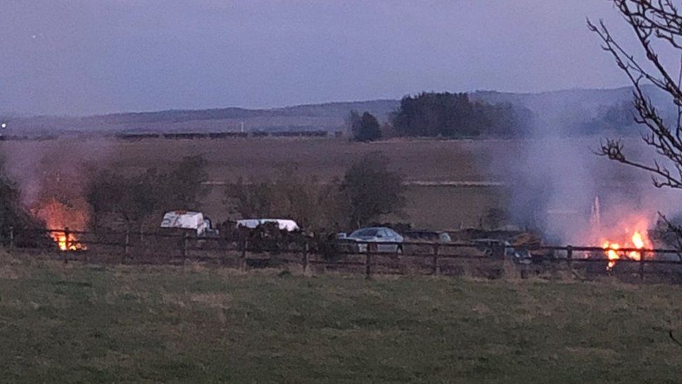 Cars in a field with fires around them
