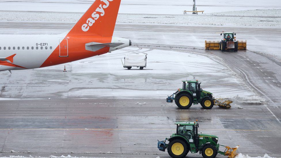 Tractors clear snow from a runway at Manchester Airport