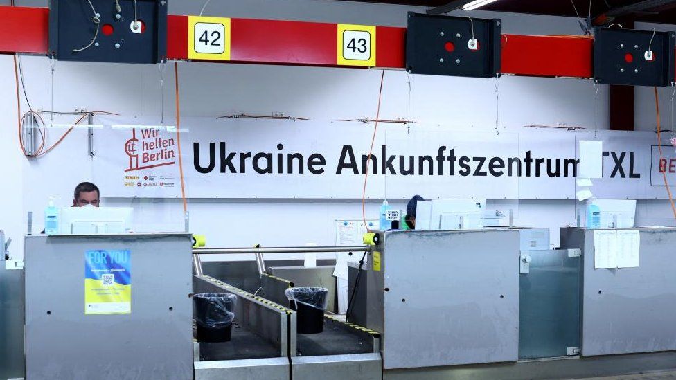 พนักงานนั่งบนโต๊ะทำงานที่ศูนย์ที่พักสำหรับผู้ลี้ภัย รวมถึงชาวยูเครน ภายในสนามบินเก่าเทเกล ในกรุงเบอร์ลิน ประเทศเยอรมนี 9 พฤศจิกายน 2565