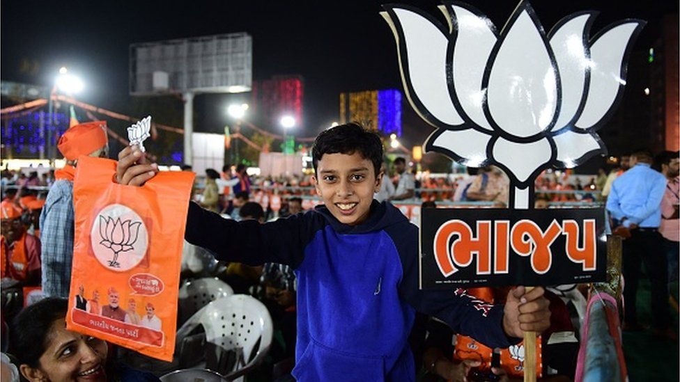 Мальчик держит плакат партии Бхартия Джанта (БДП) во время митинга БДП, на котором присутствовал министр внутренних дел Индии Амит Шах, перед выборами в Ассамблею Гуджарата в Ахмадабаде 26 ноября 2022 года.