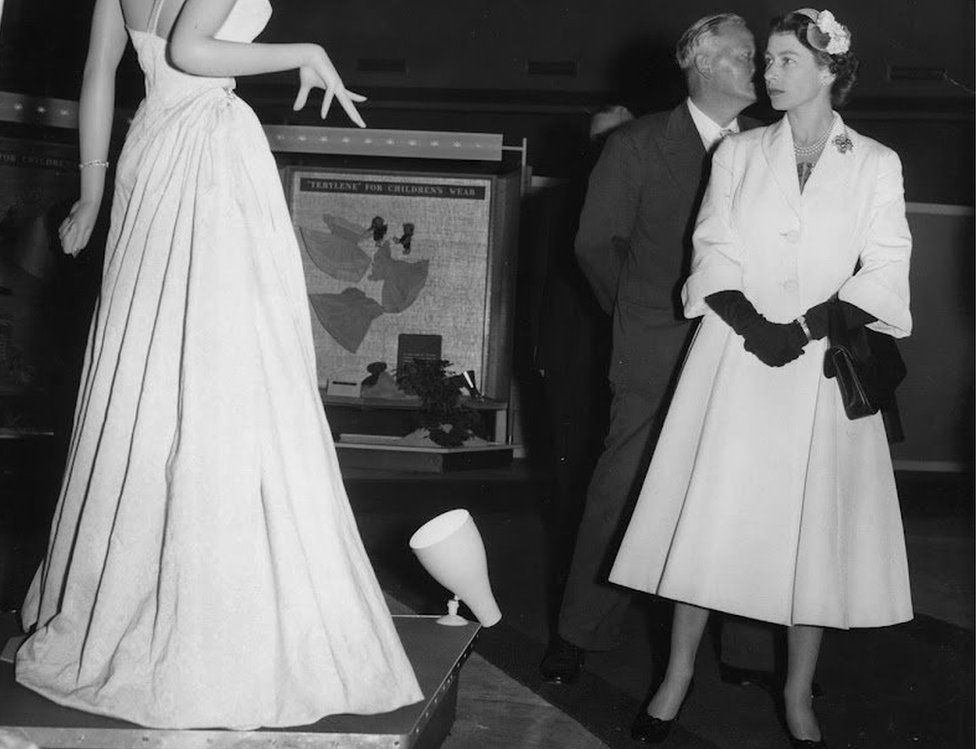 The Queen looks at a dress on a mannequin