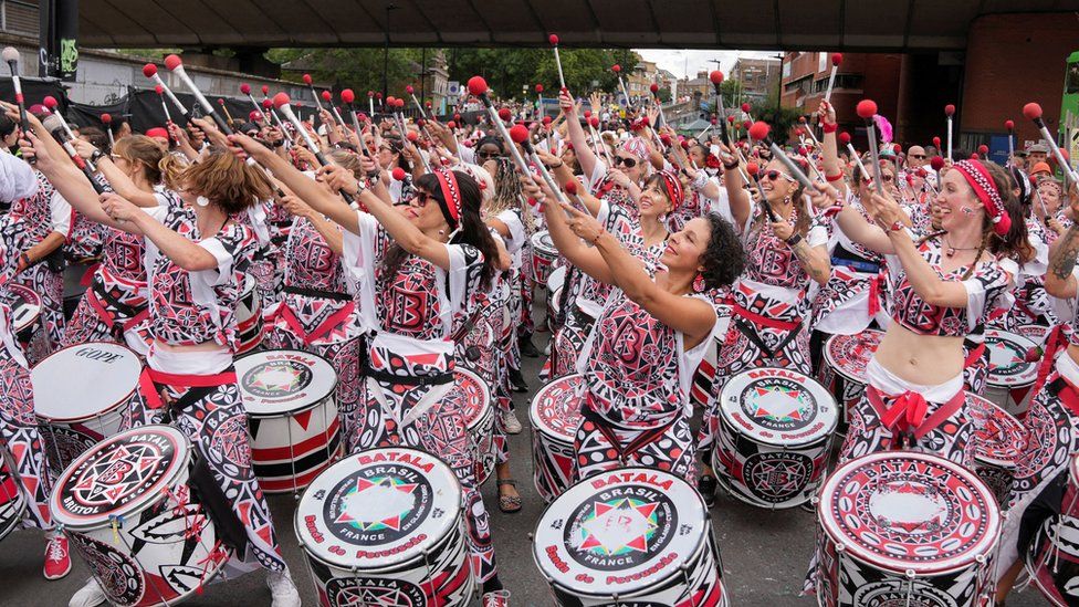 A Brazilian band performing in red, black and white costumes in August 2022