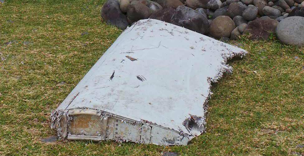 French gendarmes and police stand near a large piece of plane debris which was found on the beach in Saint-Andre, on the French Indian Ocean island of La Reunion, July 29, 2015