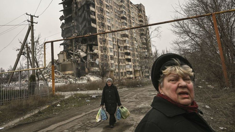 An elderly woman walks in front of a destroyed apartment building in the city of Avdiivka in Ukraine.