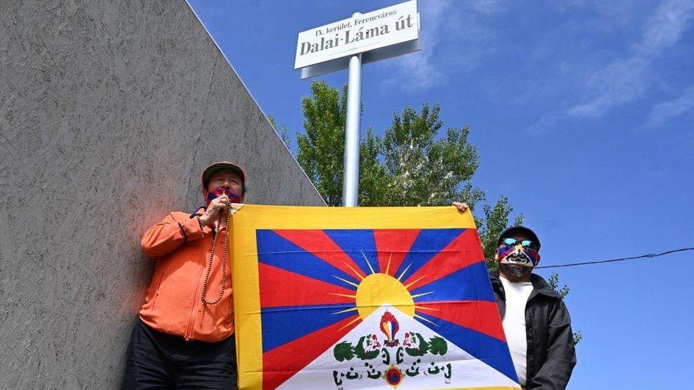 Activists hold the Tibetan flag underneath a street sign reading Dalai Lama Street in Budapest