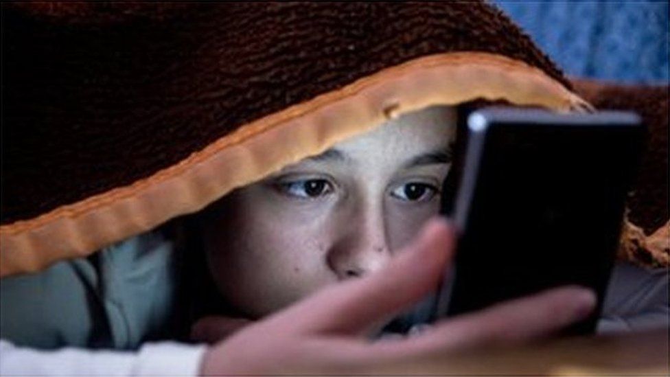 Teenage girl using her phone in bed
