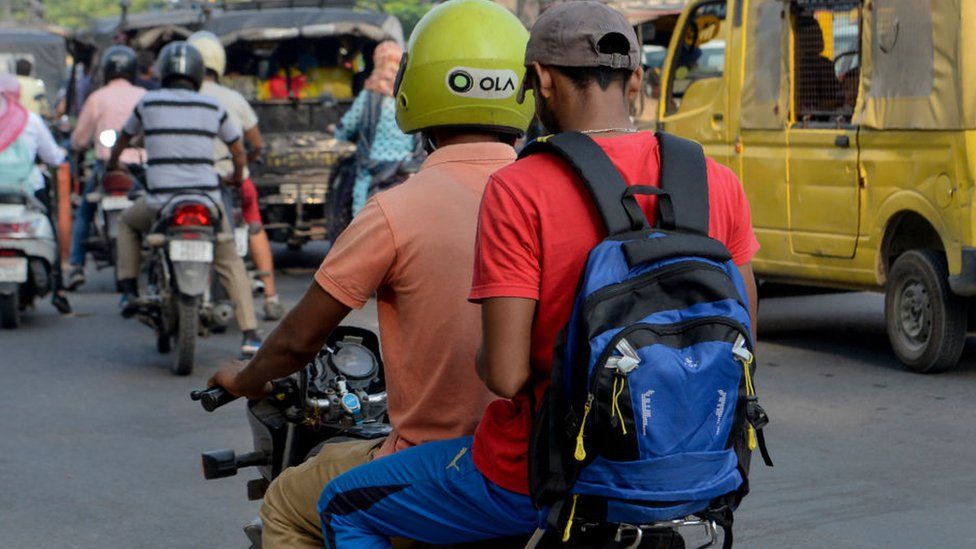 In this photograph taken on September 12, 2019, an Ola motorcyclist transports a passenger in Amritsar.