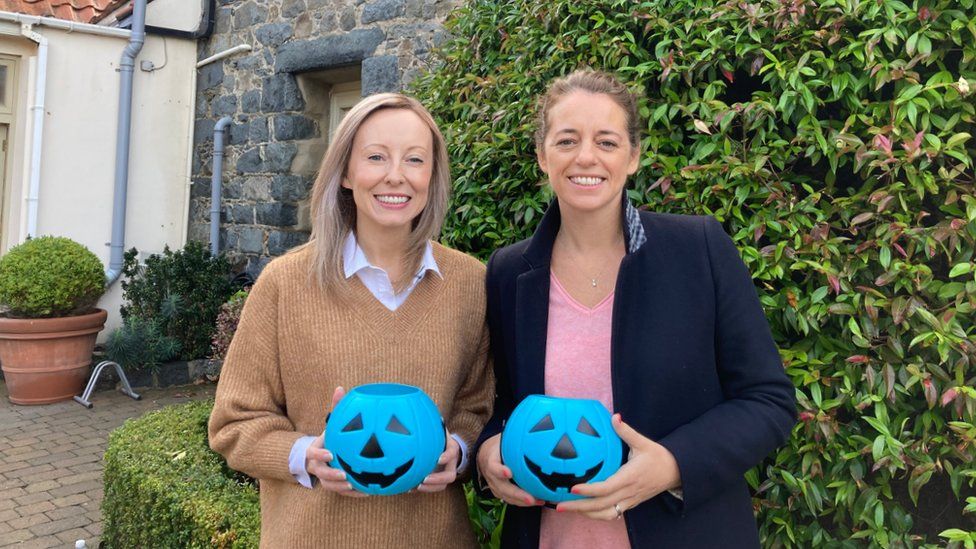 Two woman holding blue Halloween buckets