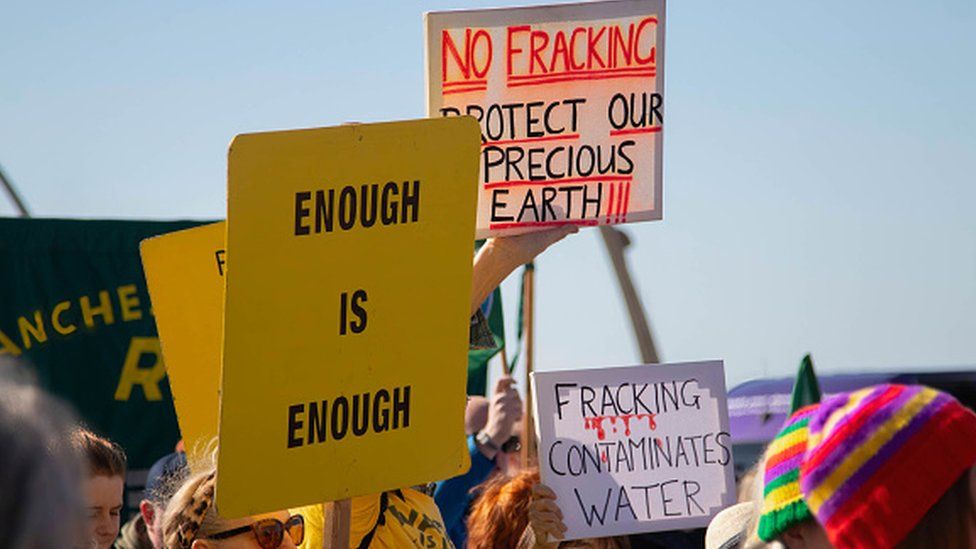 Protesters hold placards at a protest against fracking