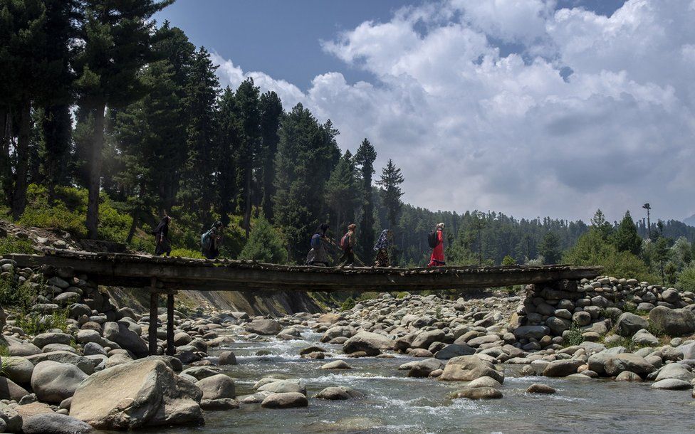 Students walking to school on a bridge in Kashmir.